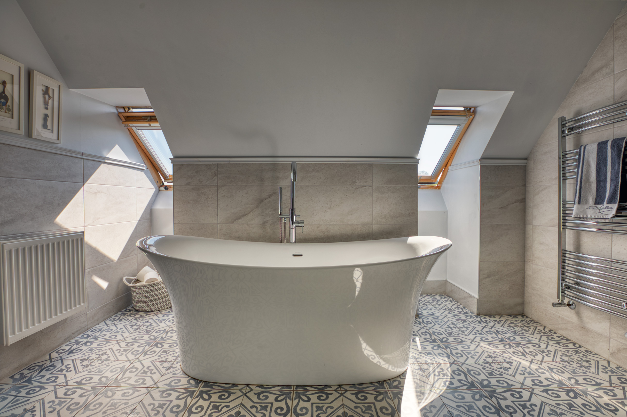 Freestanding bathtub in a modern bathroom with patterned tile floor.
