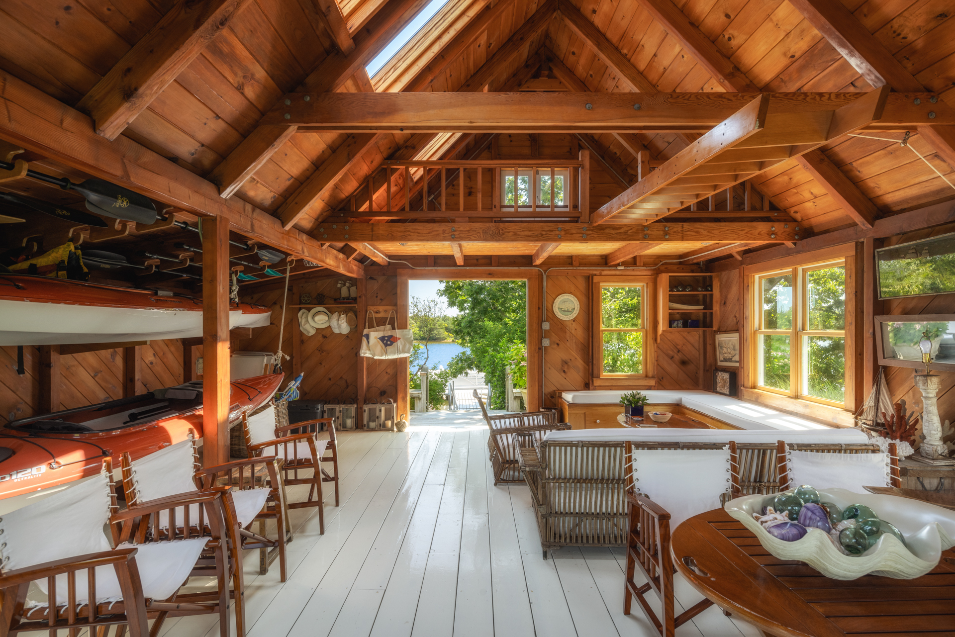 Interior of a charming boathouse with kayaks and wicker furniture.