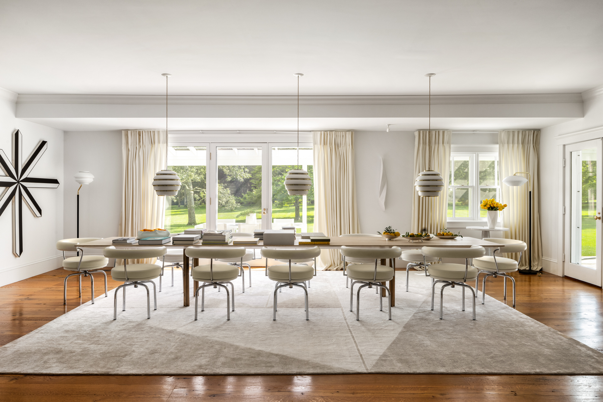 Cozy dining room with a large wooden table and off-white chairs overlooking the garden.