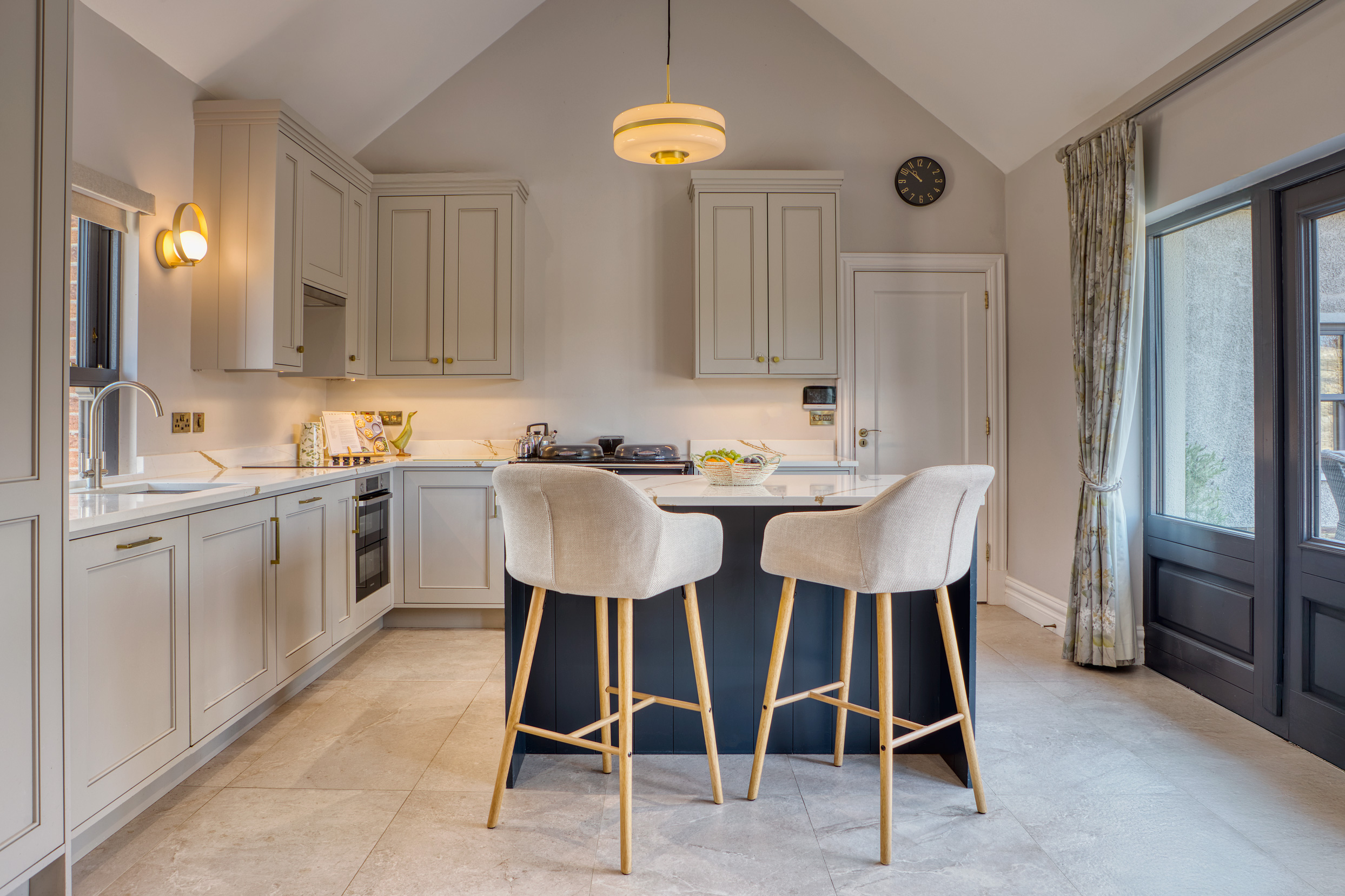Kitchen with light beige cabinets and a kitchen island with two bar stools.