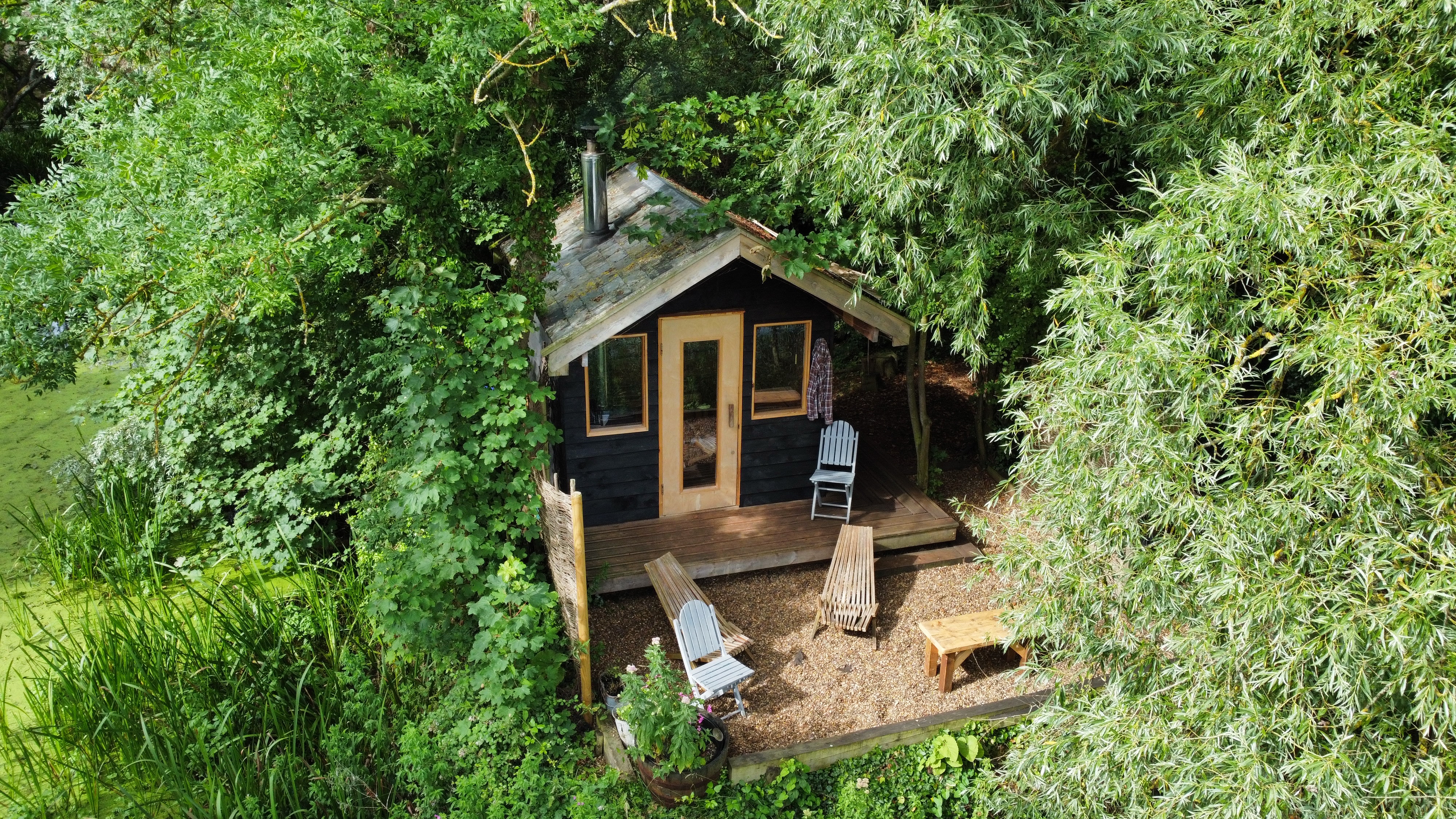 Aerial view of a small cabin in a wooded area.