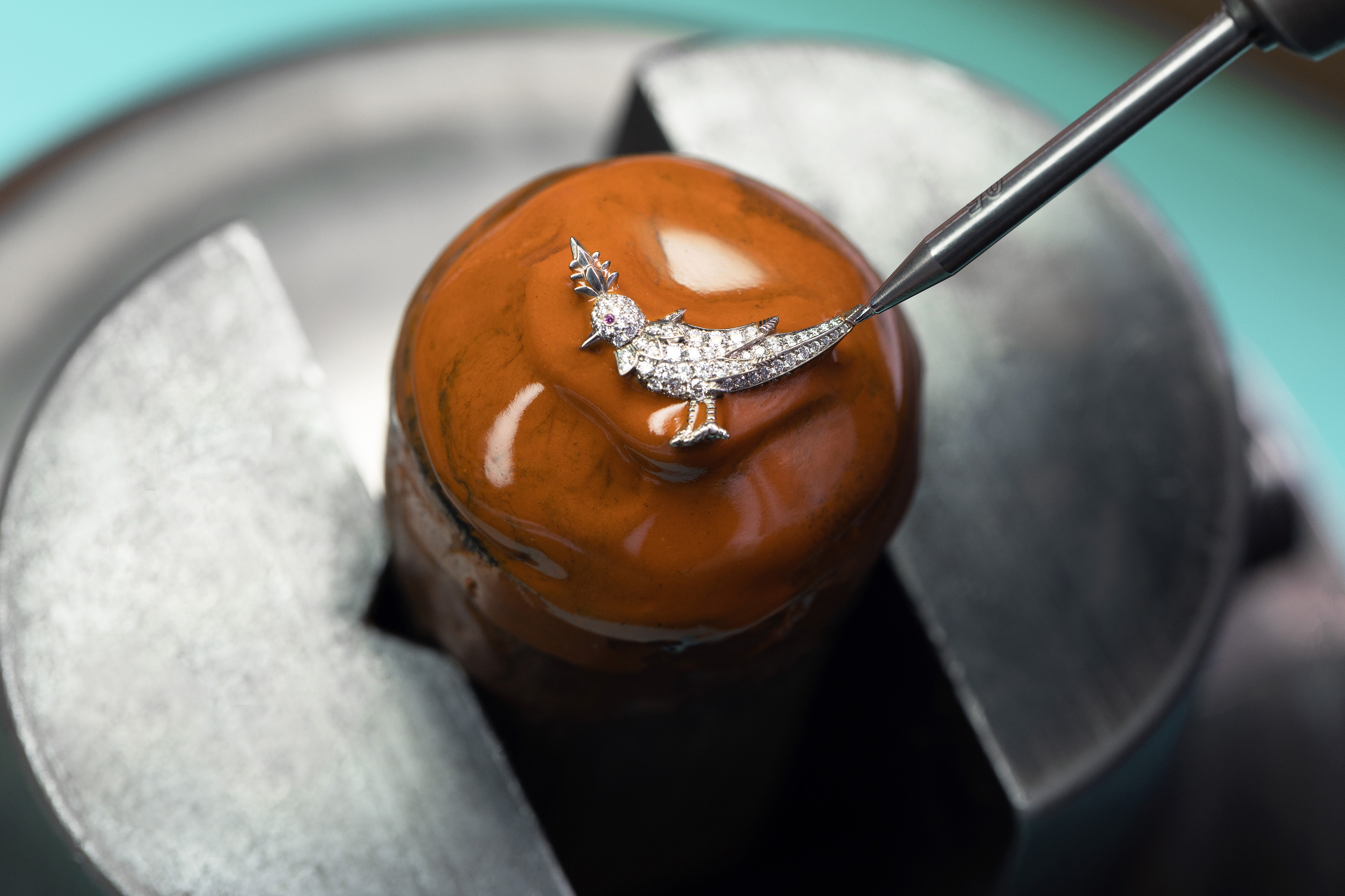 Close-up of a jeweler working on a diamond bird pendant.