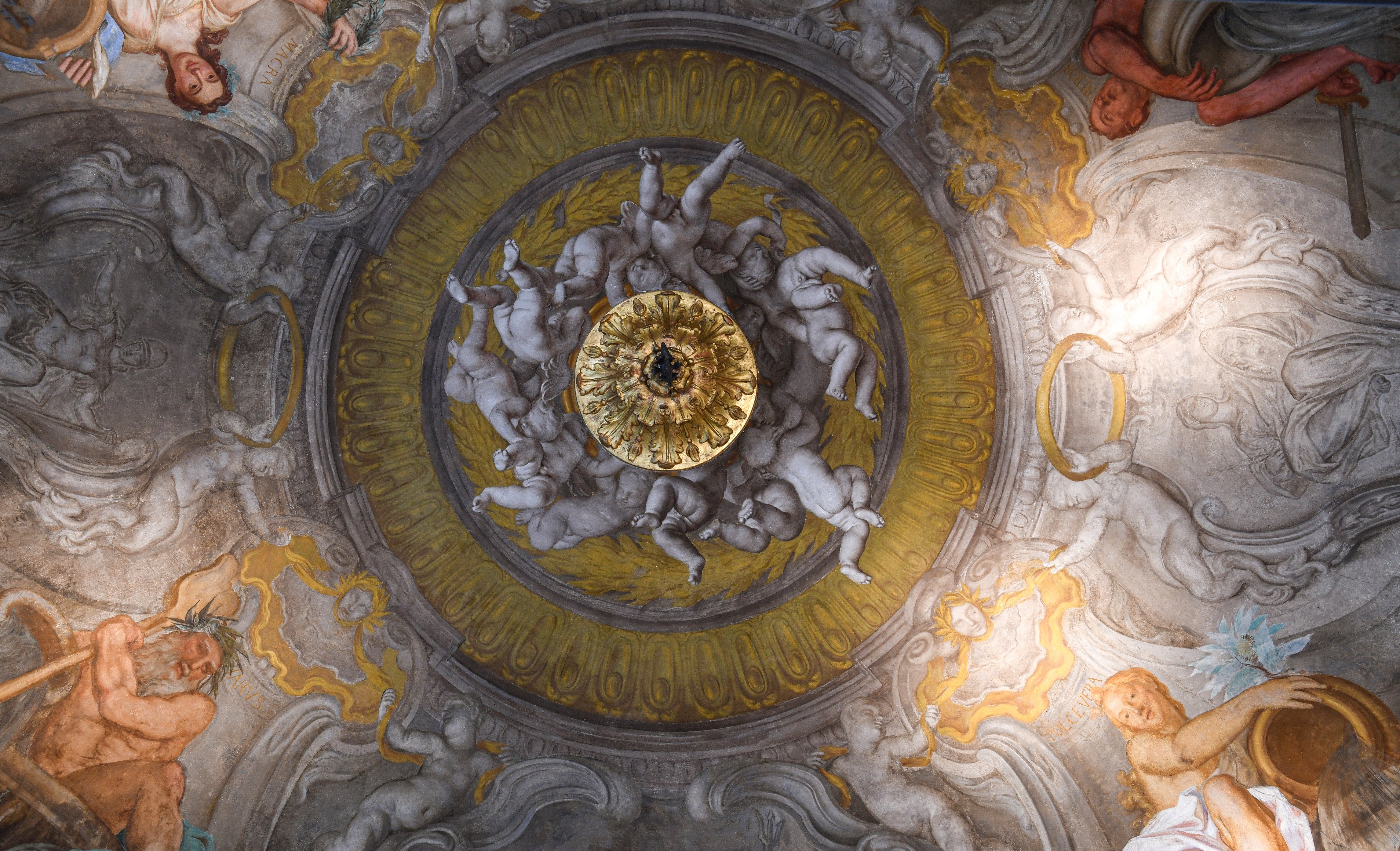 Frescoed ceiling featuring cherubs and classical figures at the Palazzo Durazzo Hotel.