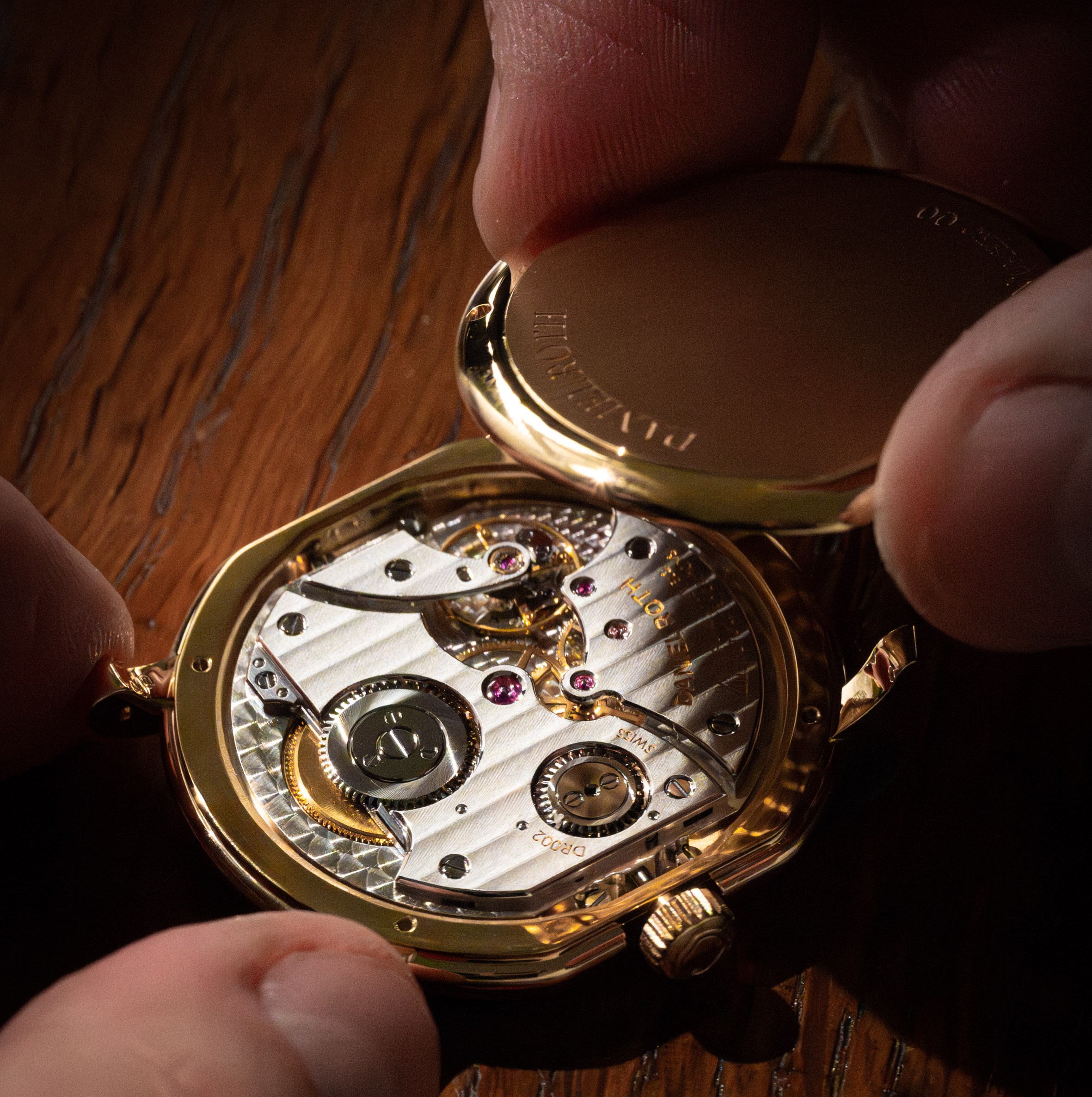 Close-up of a gold watch's inner workings being revealed.