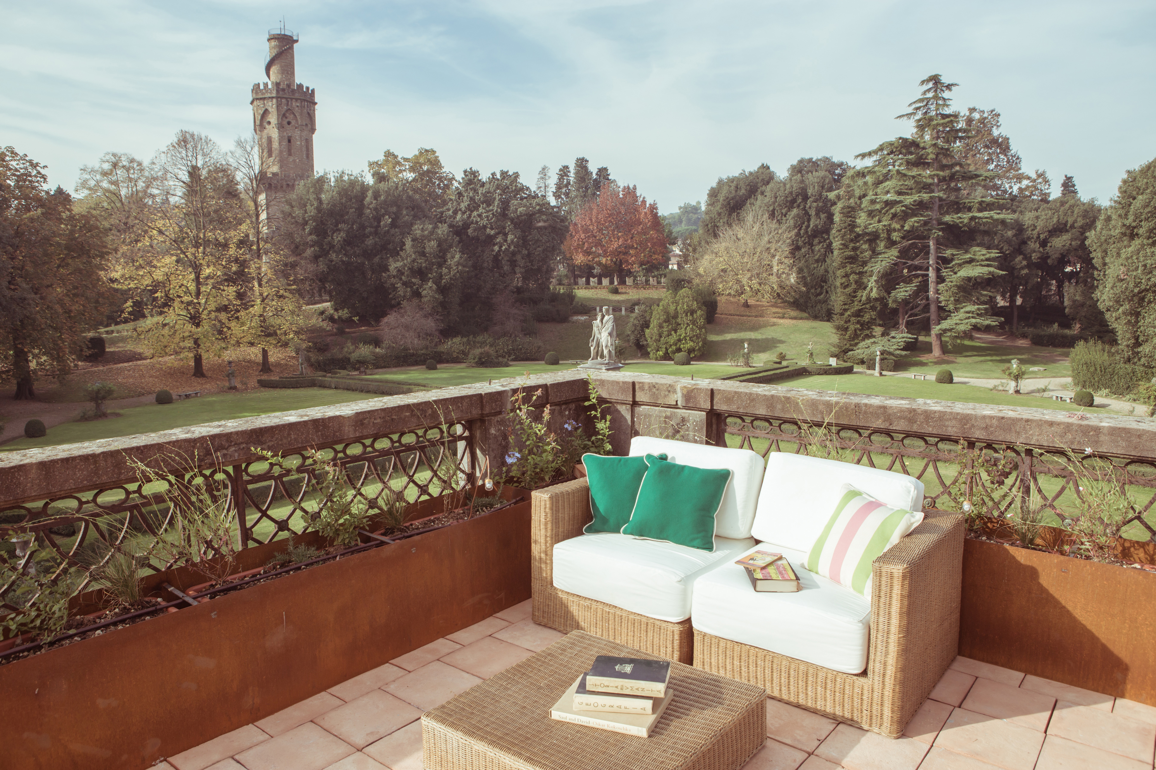 A sofa on a terrace overlooking lawns and an ancient tower at AdAstra hotel in Florence, Italy