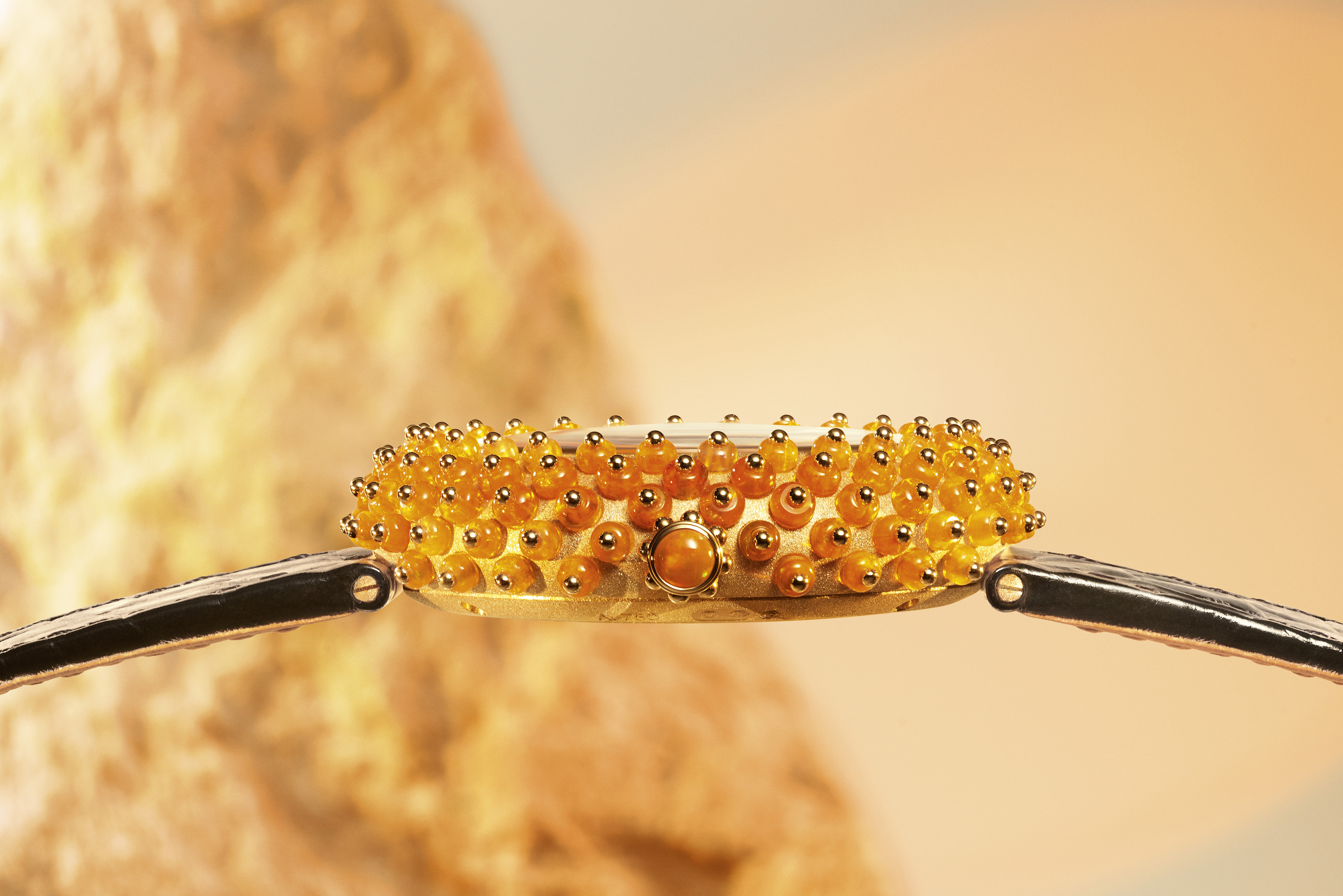 Gold watch adorned with orange stones.