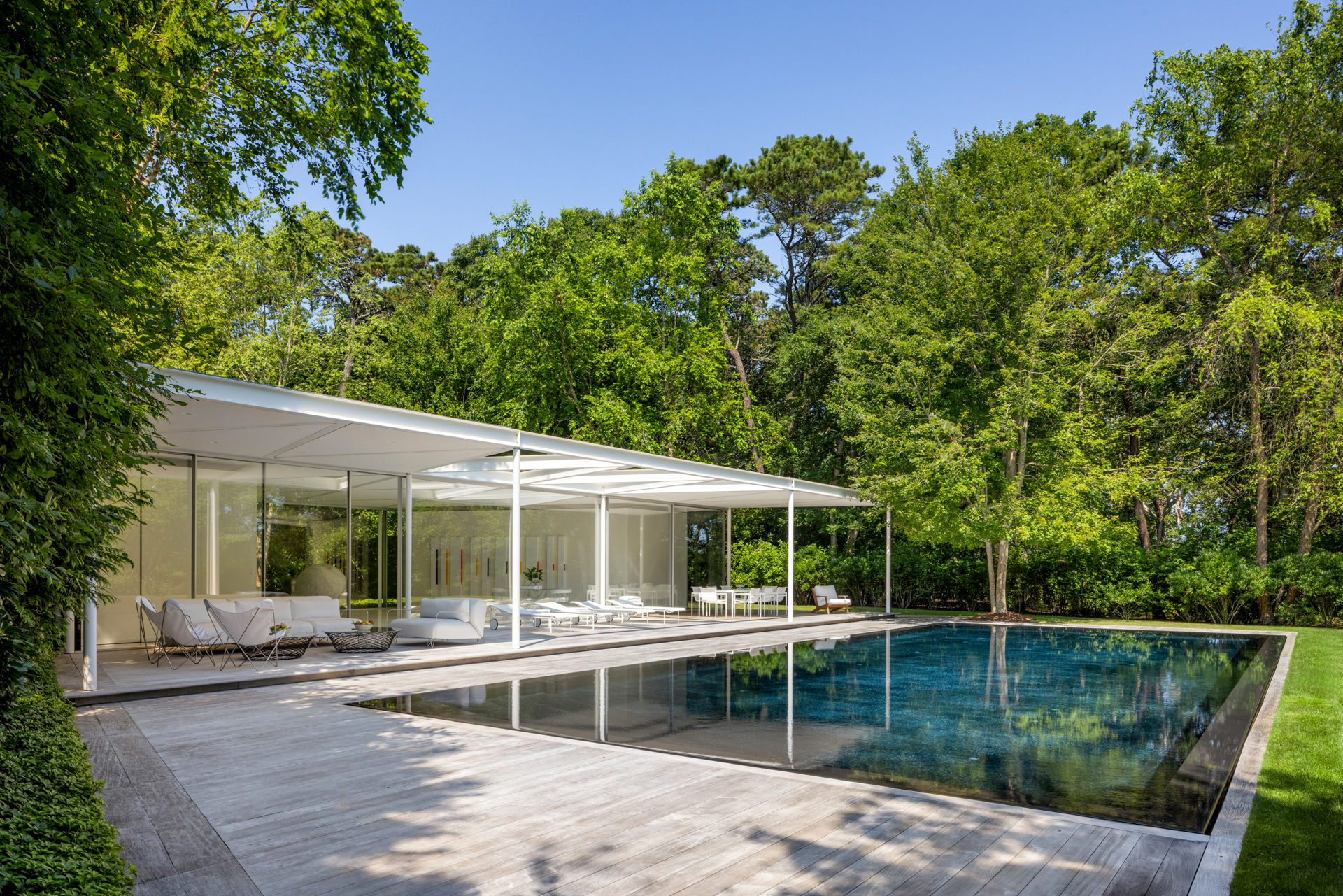 The main house with a modern pavilion, pool, and surrounding woods.