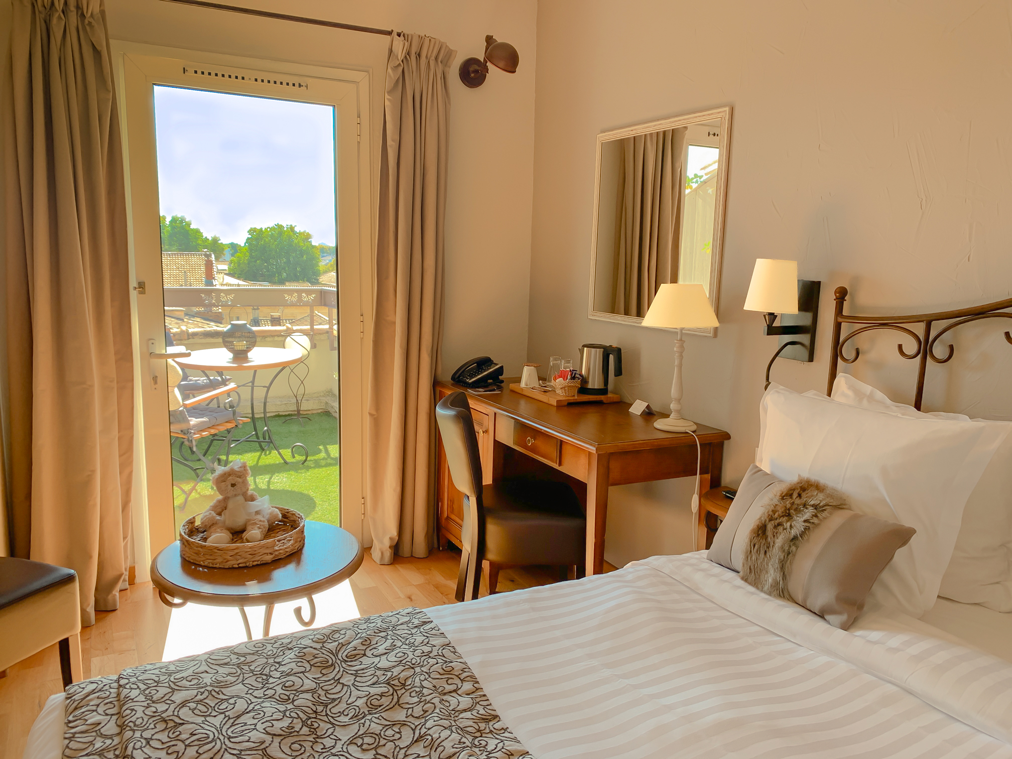 Hotel room with a bed, desk, and balcony view.