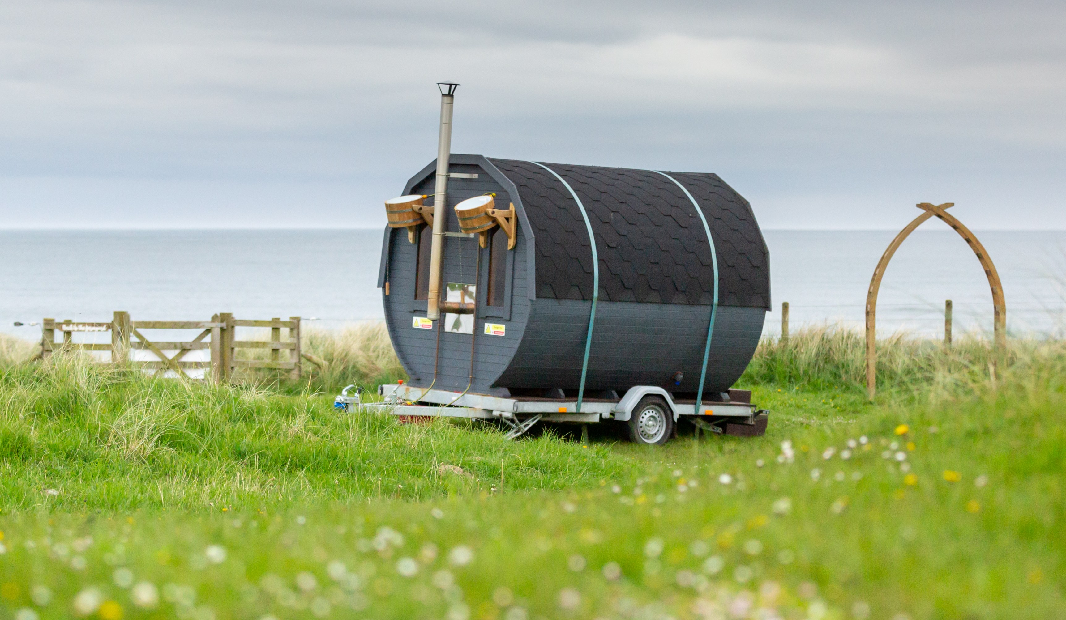 Barrel sauna on a trailer near the ocean.