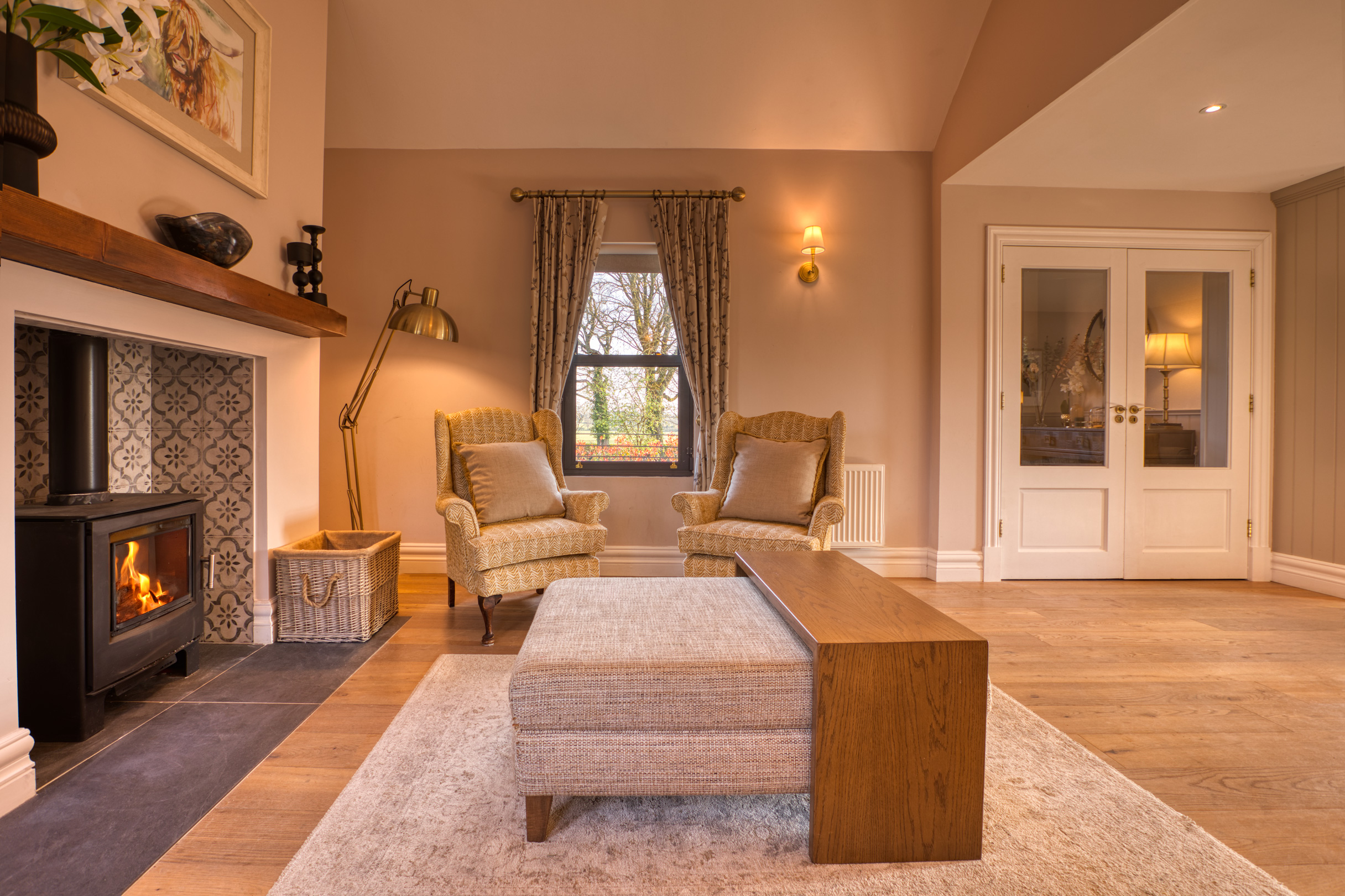 Cozy living room with fireplace, armchairs, and ottoman.